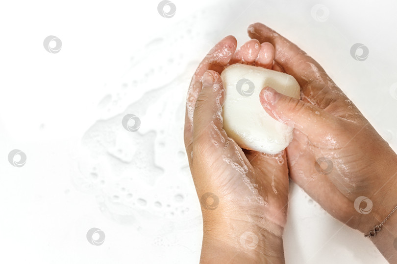 Скачать Крупный план рук молодой женщины с куском мыла ручной работы на белом фоне.Мытье рук с мылом. Он моет руки. фотосток Ozero