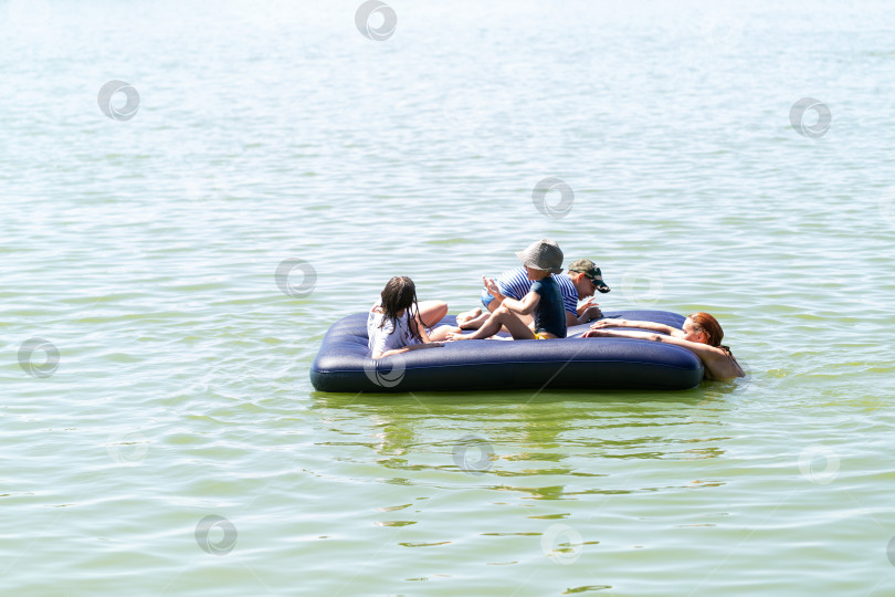 Скачать Дети плавают на надувном матрасе на озере, жаркий летний день, праздники, выходные, отдыхают фотосток Ozero