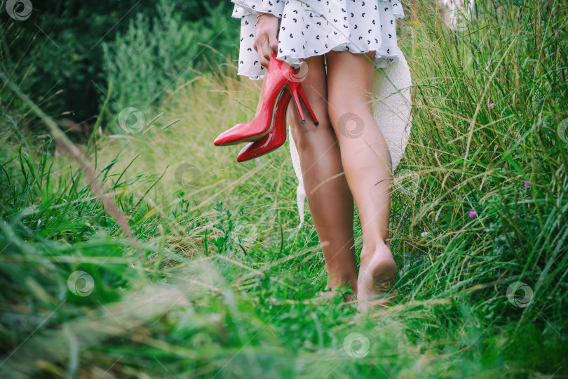 Скачать женщина идет босиком по траве, держа туфли в руках фотосток Ozero