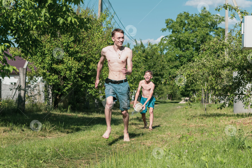 Скачать Два брата поливают водой участок за городом фотосток Ozero