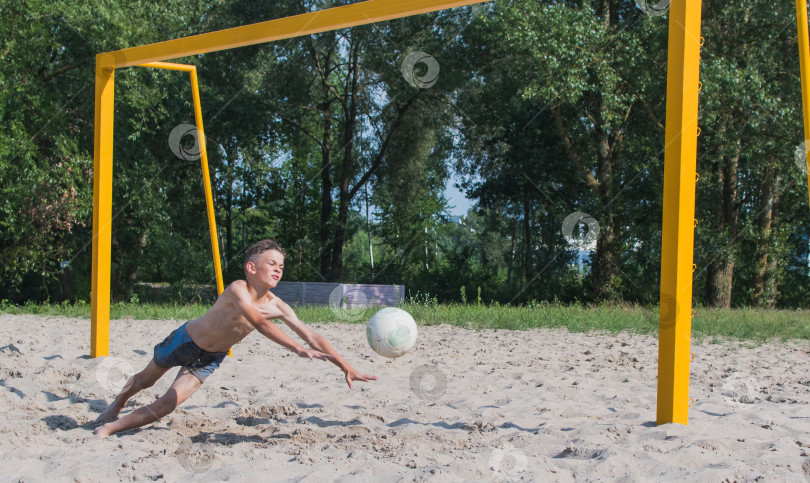 Скачать Маленький мальчик играет в футбол на песке фотосток Ozero