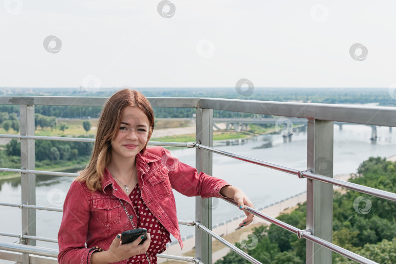 Скачать Молодая девушка смотрит на город с панорамного балкона фотосток Ozero