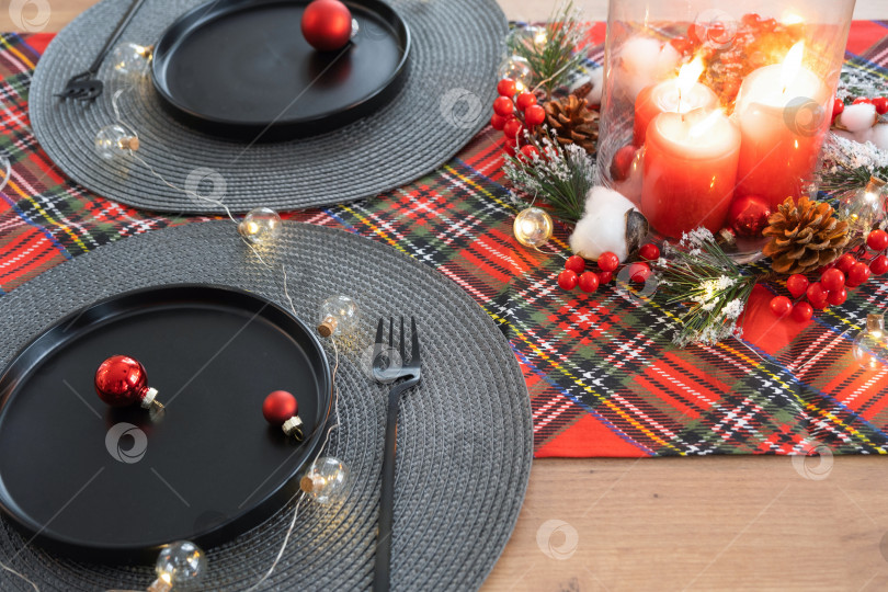 Скачать Праздничный стол, накрытый в гостиной на Рождество и Новый год в стиле лофт. Рождественская елка, черные тарелки и вилки, тканые салфетки, модная посуда, уютный интерьер дома фотосток Ozero