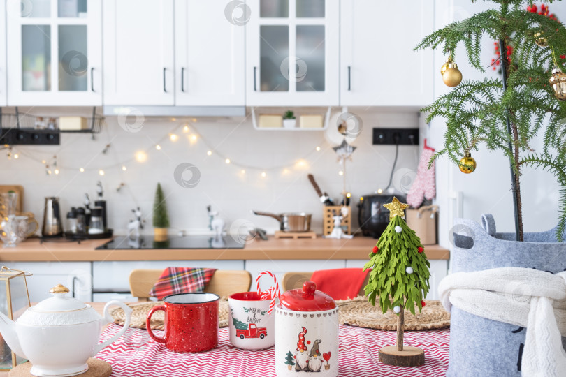 Скачать Праздничный рождественский декор на белой кухне, праздничный завтрак, белый скандинавский интерьер. Араукарию, как рождественскую елку, украшают и заворачивают в шарф и войлочные кашпо. Новый год, настроение, уютный дом фотосток Ozero
