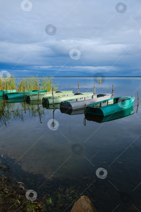 Скачать лодки на озере у берега и облачное небо, отражающееся в воде фотосток Ozero