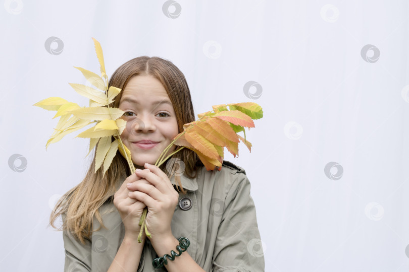 Скачать Молодая девушка в плаще с осенними листьями фотосток Ozero