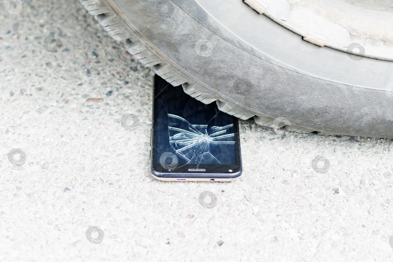 Скачать Разбитый телефон лежит под колесами автомобиля фотосток Ozero