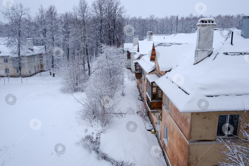 Скачать дома с дымоходами на крышах среди деревьев зимним днем фотосток Ozero