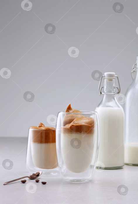Скачать Охлажденный пышный сливочно-взбитый напиток с кофейной пенкой и молоком в бокале с двойными стенками. фотосток Ozero