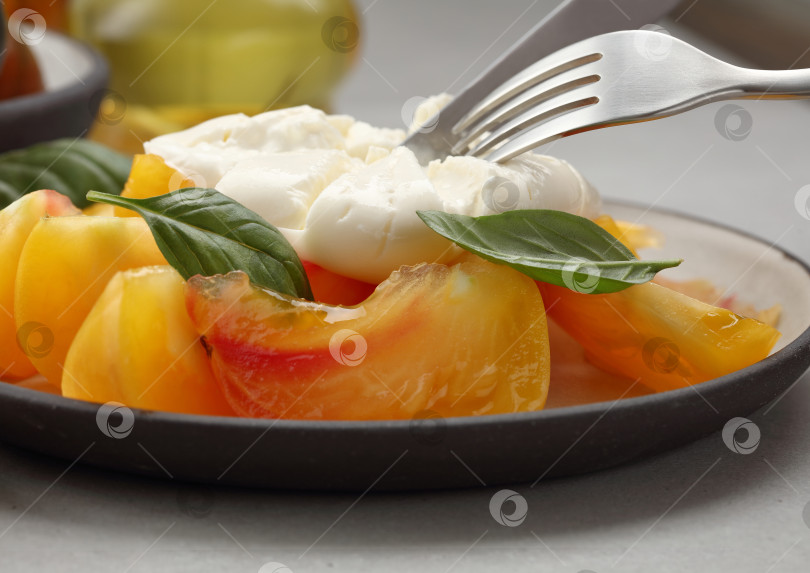 Скачать Сыр буррата или моцарелла с желто-красными помидорами и листьями базилика в тарелке. фотосток Ozero