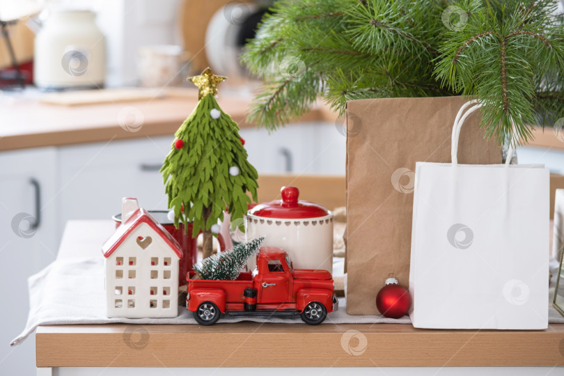 Скачать Макет бумажных упаковок лежит на кухонном сервированном столе, украшенном к Рождеству. Покупки и подарки, презенты и готовые блюда доставляются и готовятся к новому году фотосток Ozero