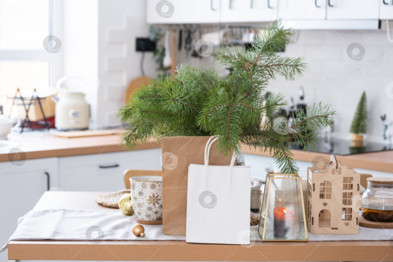 Скачать Макет бумажных упаковок лежит на кухонном сервированном столе, украшенном к Рождеству. Покупки и подарки, подарки и готовые блюда доставляются и готовятся к новому году фотосток Ozero