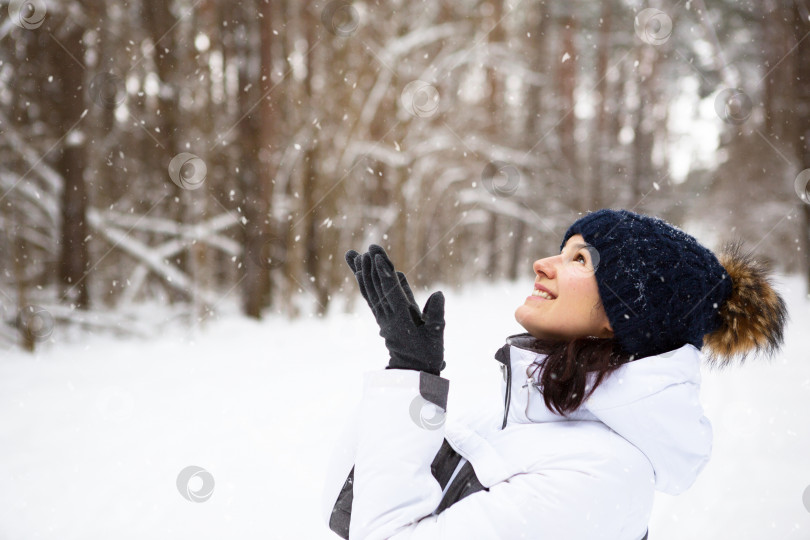 Скачать Женщина в теплой вязаной шапке, надвинутой на глаза, улыбается и наслаждается снегом, холодной погодой. Мероприятия на свежем воздухе, сезон, зима, тает снег. Покрытая инеем, прекрасная улыбка. Портрет крупным планом фотосток Ozero