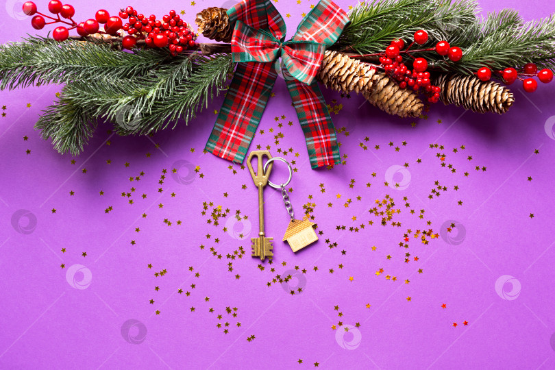 Скачать Ключ от дома с брелком для ключей коттедж на праздничном фоне с рождественской елкой, огнями гирлянд. С Новым годом-фиолетовый фон, подарок, поздравительная открытка. Покупка, строительство, переезд, ипотека фотосток Ozero