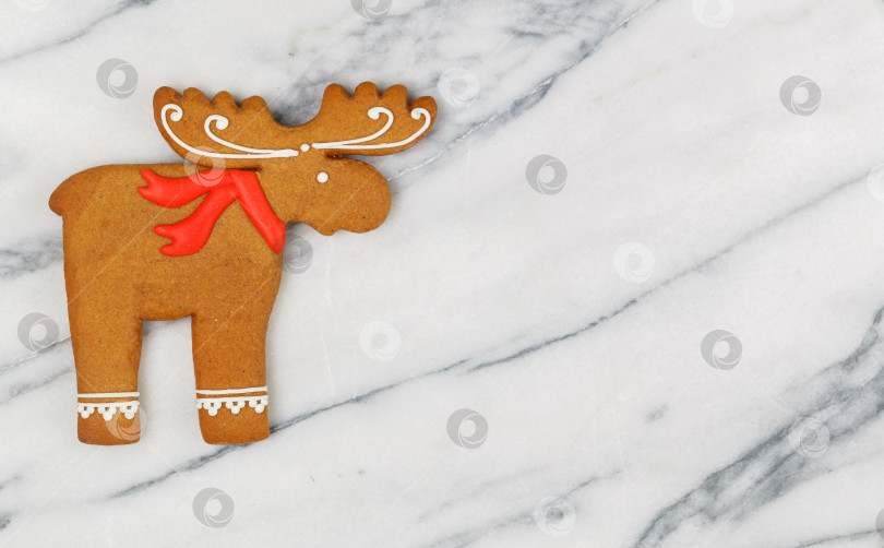 Скачать Рождественские домашние пряники, зимнее праздничное угощение в форме лося (лосихи, оленя) на мраморном фоне. Выборочный фокус, пространство для копирования фотосток Ozero
