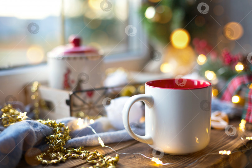 Скачать Рождественский декор у окна на уютном деревянном подоконнике с кружкой с напитком и банкой из-под печенья. Гирлянды, ветка рождественской елки, натюрморт с подносом для завтрака фотосток Ozero