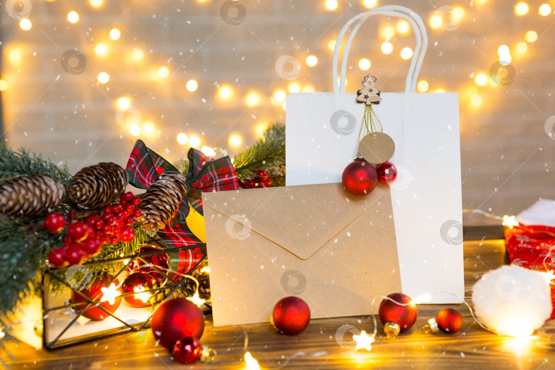 Скачать Конверт из крафт-бумаги с поздравлениями и приглашением на Рождество и новый год в праздничном декоре, с гирляндами. Письмо для Санта-Клауса. Макет, натуральный декор, ручная работа. Пространство для копирования фотосток Ozero