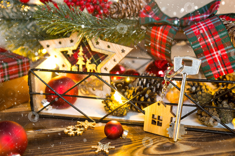 Скачать Ключ от дома с брелоком на столе с рождественским декором. Подарок на Новый год, Рождество. Строительство, дизайн, проектирование, переезд в новый дом, ипотека, аренда и покупка недвижимости. Пространство для копирования фотосток Ozero