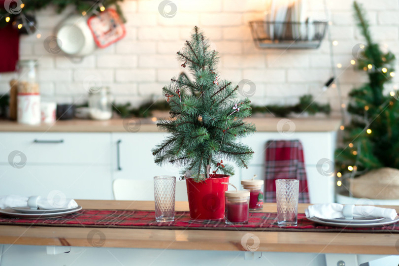 Скачать Рождественский декор на кухне, подготовка к празднованию. Подсветка из гирлянд, тарелок, ламп накаливания в стиле лофт. Рождественская елка, кухонная утварь. Канун Нового года, Рождества. Интерьер дома фотосток Ozero