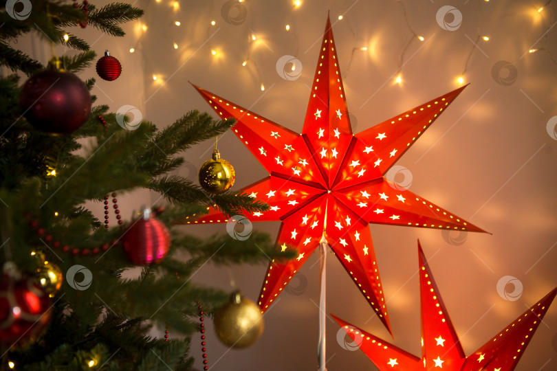 Скачать Красная рождественская звезда-лампа на подставке. Праздничное оформление интерьера дома. Рождество, новый год, еловые ветки. Фон, пространство для текста фотосток Ozero
