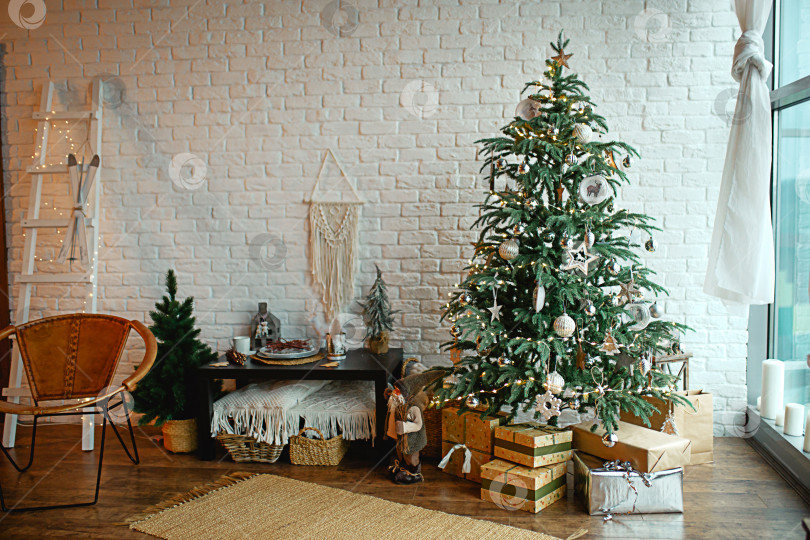 Скачать Рождественский интерьер в стиле скандинавского лофта: серый бетон, деревянный декор, лампы накаливания, реалистичная искусственная рождественская елка. Уютный новый год в загородном доме фотосток Ozero