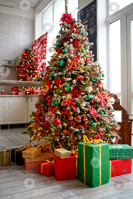 Скачать Рождественская елка украшена красными и зелеными игрушками, коробки с подарками на полу. Новогодняя атмосфера в доме, праздничный интерьер. фотосток Ozero