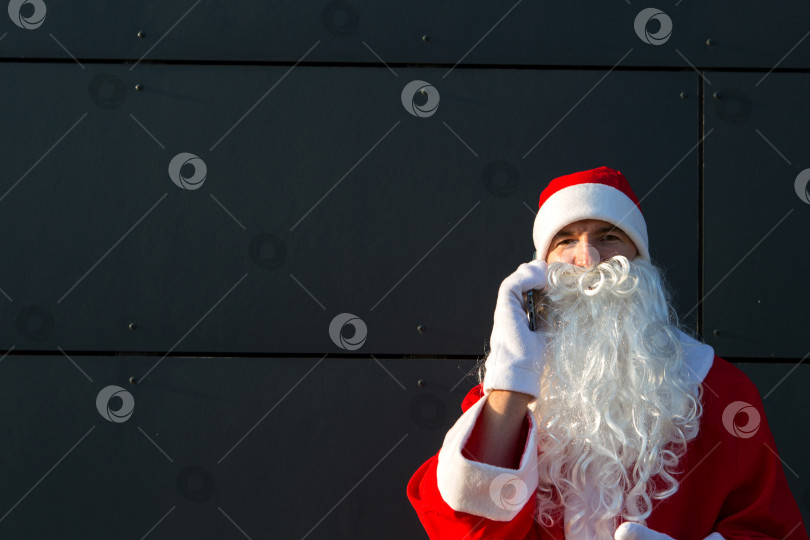 Скачать Современный Санта-Клаус разговаривает по телефону. Заказ услуг аниматора на Рождество и новый год. Онлайн-поздравления через Интернет и мобильную связь, социальная дистанция фотосток Ozero