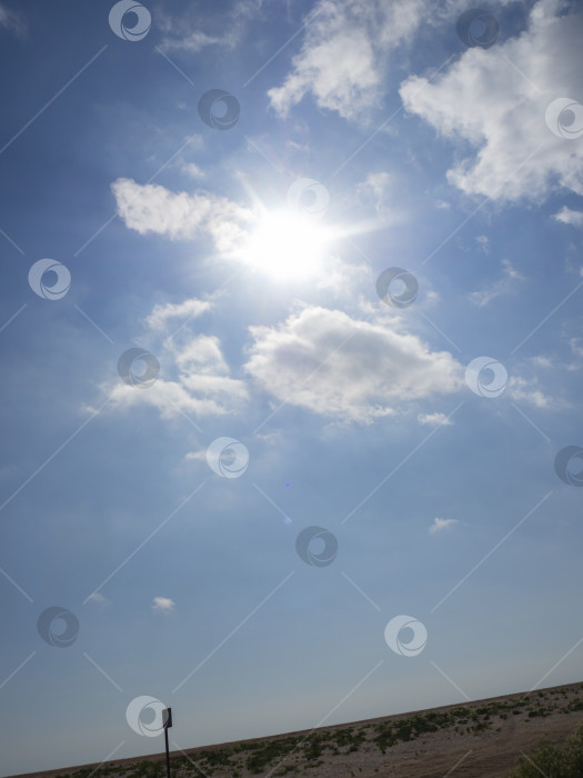 Скачать Солнце сияет между белыми облаками на голубом небе. фотосток Ozero