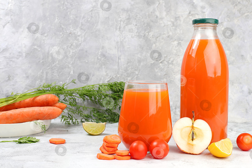 Скачать Детокс-напиток в стеклянной банке и бокале, ломтики моркови, яблок и помидоров на сером фоне. Свежий натуральный морковно-яблочный смузи или сок, концепция похудения, свежие фрукты и овощи, избирательный подход фотосток Ozero