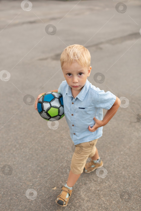 Скачать Маленький мальчик идет с детским футбольным мячом фотосток Ozero