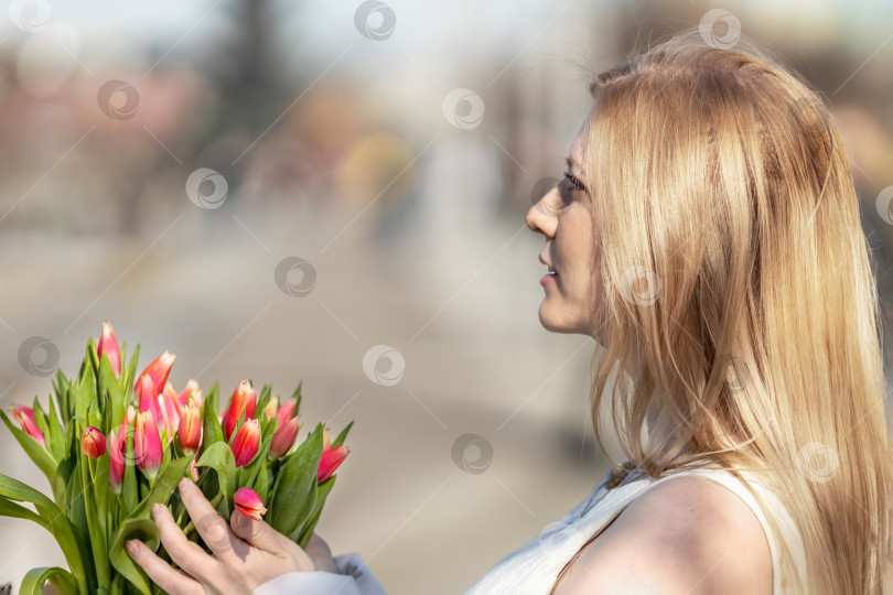 Скачать Молодая блондинка с букетом красных тюльпанов на набережной. Концепция весеннего праздника - это 8 марта, Пасха, Женский день. фотосток Ozero