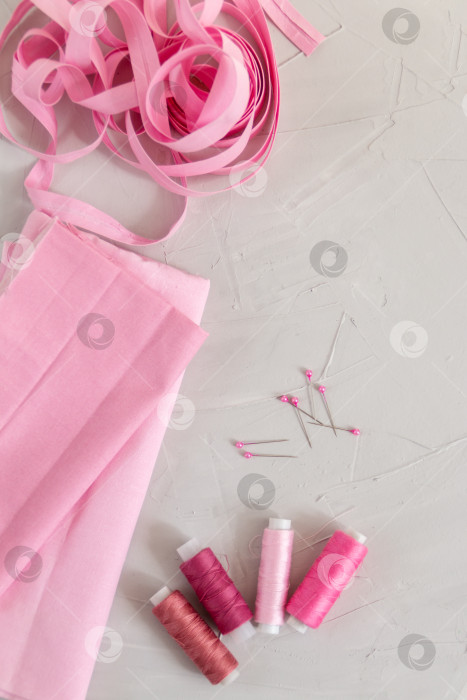 Скачать Нитки и хлопчатобумажная ткань розового цвета на сером фоне фотосток Ozero