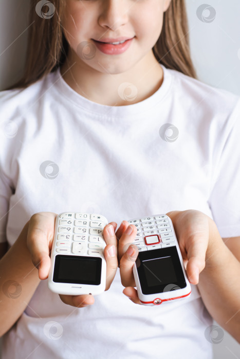 Скачать Два белых старомодных кнопочных телефона в руках девушки вертикальный вид фотосток Ozero