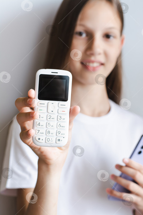 Скачать Белый кнопочный телефон в руке девушки со смартфоном в вертикальном положении фотосток Ozero