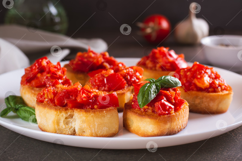Скачать Аппетитные кростини на хлебе с жареными помидорами и чесноком на тарелке фотосток Ozero