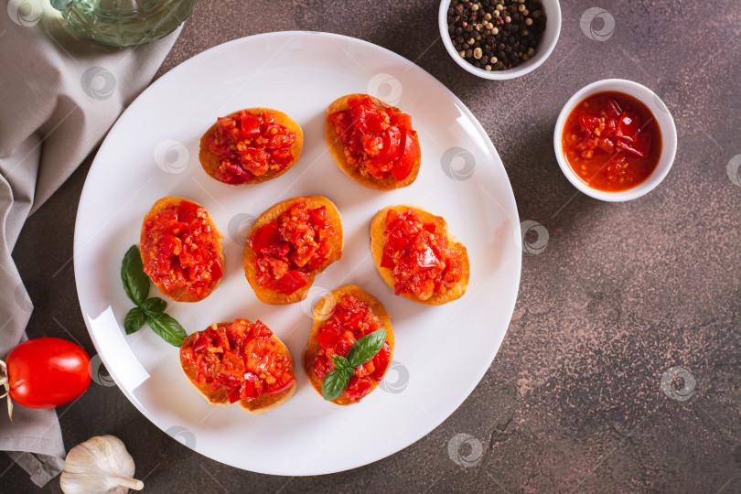 Скачать Аппетитные кростини на хлебе с жареными помидорами и чесноком на тарелке вид сверху фотосток Ozero
