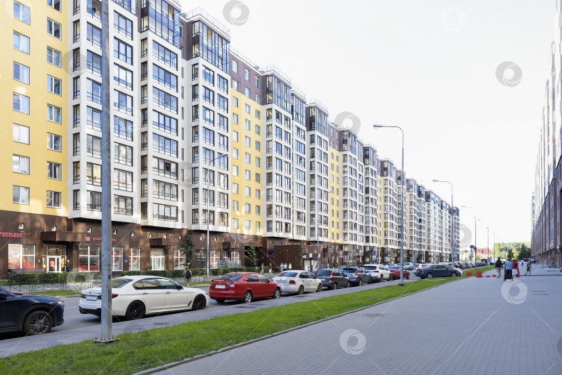 Скачать Многоэтажный дом с магазинами на первом этаже и припаркованные машины - Санкт-Петербург, Россия, Июль 2023 фотосток Ozero