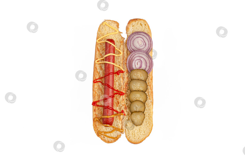 Скачать Ингредиенты для хот-догов. Нарезанная булочка содержит ингредиенты: колбасу, соус, маринованные огурцы и лук. Вид сверху. Белый фон. Изолированный. фотосток Ozero