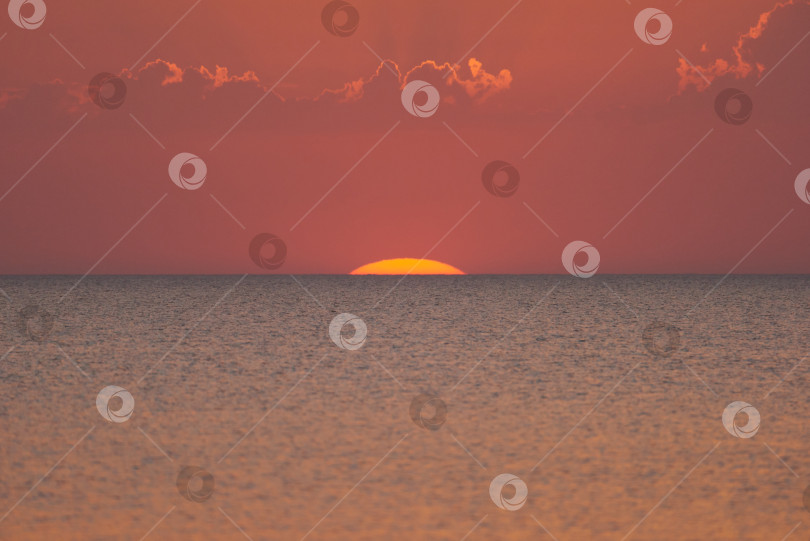 Скачать Закат. Часть красного солнца все еще видна над морским горизонтом фотосток Ozero