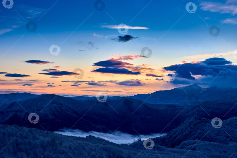 Скачать Восход солнца из-за горного хребта. Панорама гор на восходе солнца. Темно-синие облака на солнце. Зимний лес. фотосток Ozero