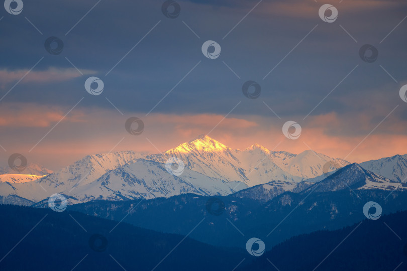 Скачать Заснеженная гора в лучах заката под грозовым небом. Гора Тыбга, Северный Кавказ фотосток Ozero