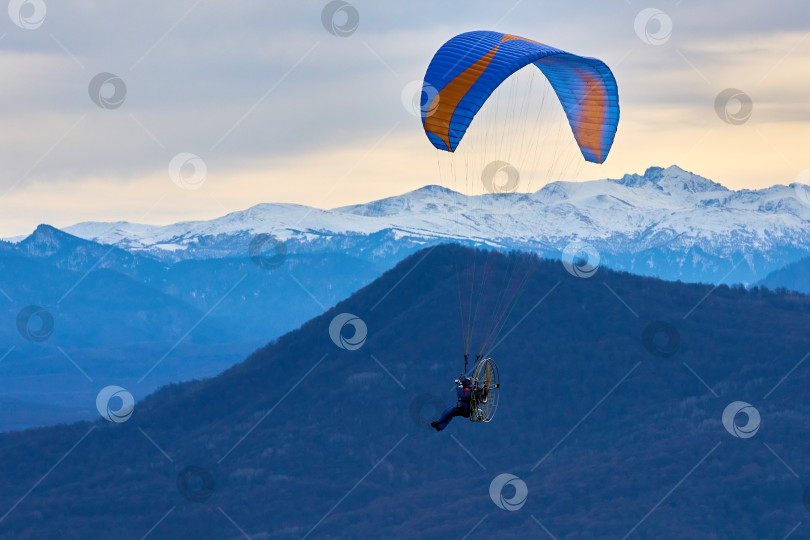 Скачать Полет на мотопараплане на фоне грозового неба и заснеженных гор фотосток Ozero
