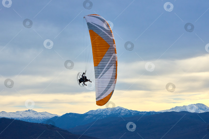 Скачать Экстремальный полет на мотопараплане на фоне грозового неба и заснеженных гор фотосток Ozero