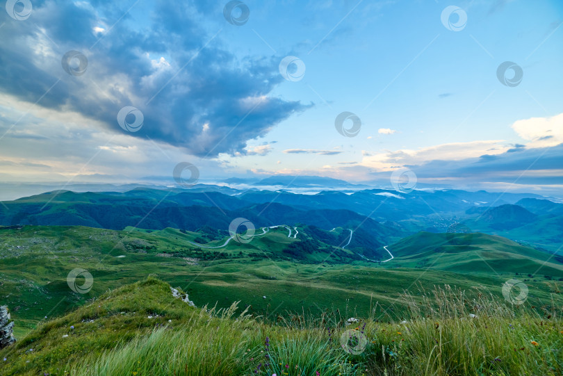 Скачать Кучевые облака на рассвете над зеленой горной долиной с извилистой дорогой и деревней фотосток Ozero