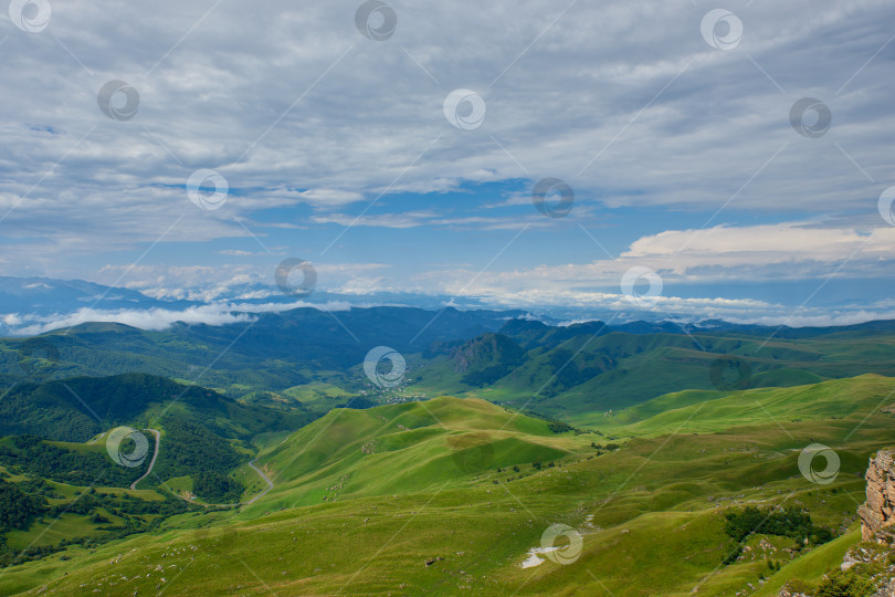 Скачать Кучевые облака над зеленой горной долиной с извилистой дорогой и деревней фотосток Ozero