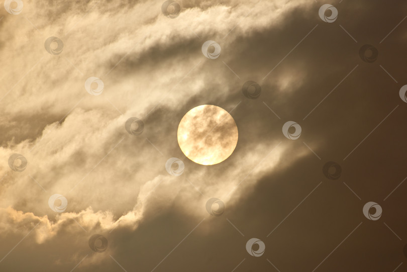 Скачать Солнечный диск просвечивает сквозь облака и туман. Солнце светит сквозь облака и туман. фотосток Ozero