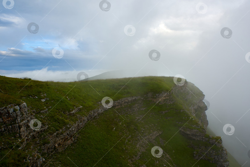Скачать Горный хребет, покрытый зеленой травой, с выступающими в тумане камнями фотосток Ozero