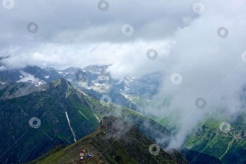 Скачать Горный зеленый хребет, покрытый соснами, в тумане и облаках. Домбай, Карачаево-Черкесия, Россия фотосток Ozero