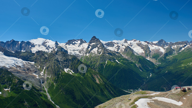 Скачать Вид на горный хребет, на переднем плане маленькие домики. Домбай, Северный Кавказ, Россия фотосток Ozero