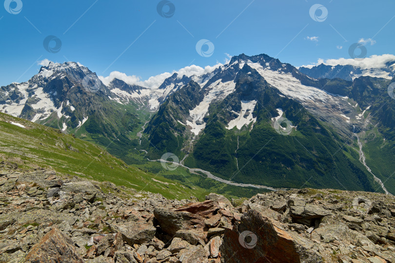 Скачать Горный хребет с ледником на переднем плане - это острые камни. Домбай, Северный Кавказ, Россия фотосток Ozero
